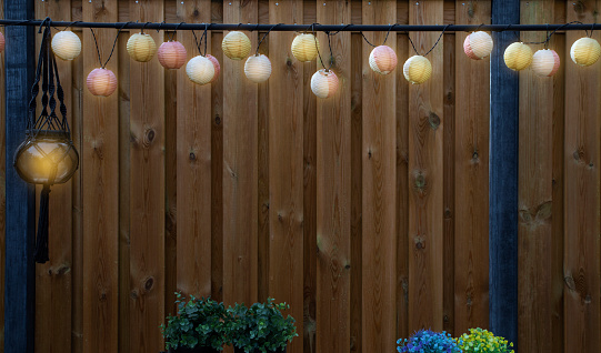 Glowing lanterns lampion lights with delicate design hanging wooden fence,decorative stylish design with copy space. cozy garden decoration space for text