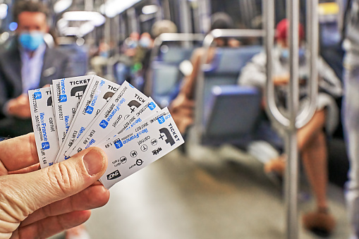 Paris, France - September 30, 2021: Fanned out metro tickets in hand in front of defocused subway interior.