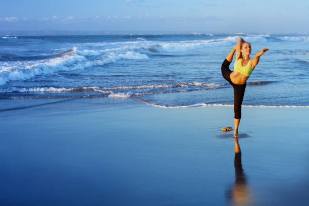 istock Woman stretching at yoga pose on sunset beach 1353375663