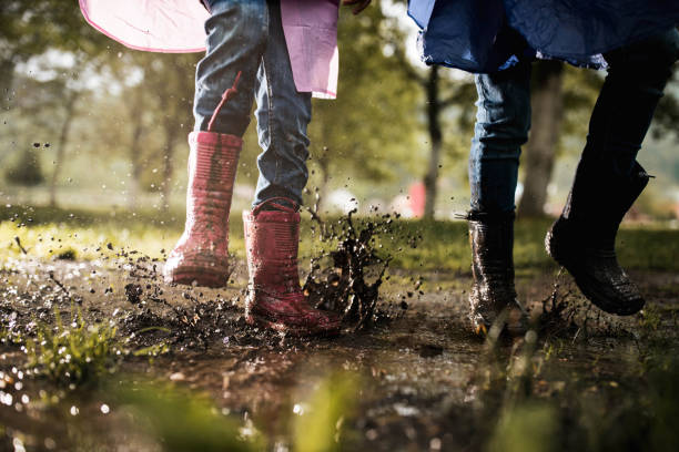 istock Unrecognizable kids running through muddy puddle in nature. 1353377173