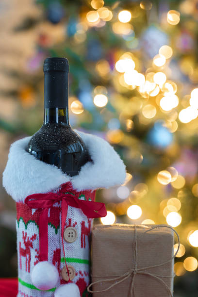 istock A red wine and bottle with blurred bokeh lights on Christmas tree in background. Christmas gift, Holiday, present concept with copy space 1353377292