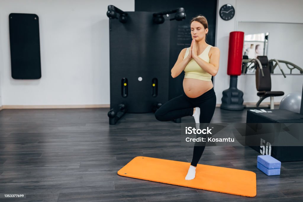 The fit pregnant woman balances on one leg and thus balances the left and right sides of the brain. This body position is a little more advanced and is good for pregnant women because it improves the sense of balance, strengthens the hips and knees and has a calming effect. 30-34 Years Stock Photo