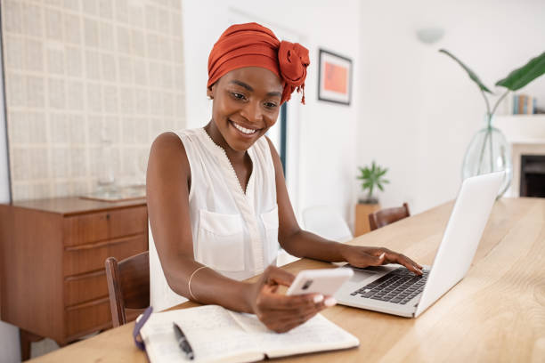 istock African american woman working on laptop while using phone at home 1353378828