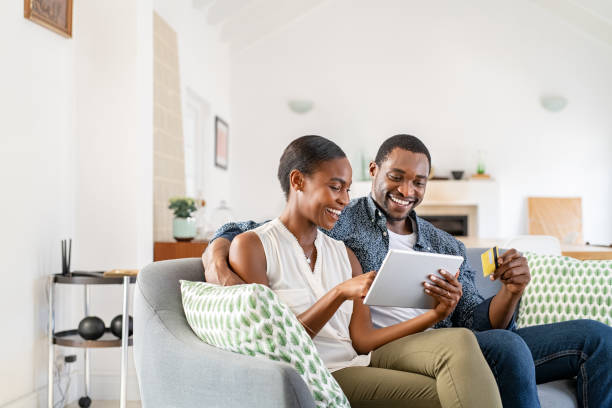 mature black couple doing online shopping with credit card card at home - computer at home imagens e fotografias de stock