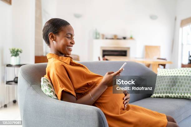 Pregnant African Woman Using Smartphone At Home Stock Photo - Download Image Now - Pregnant, Women, One Woman Only