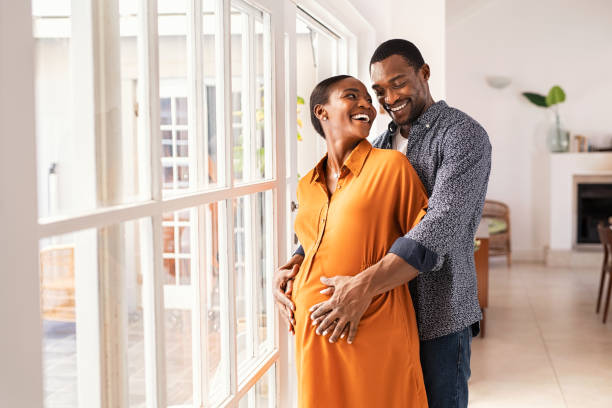 marido abrazando a mujer embarazada por detrás - couple african descent africa human relationship fotografías e imágenes de stock