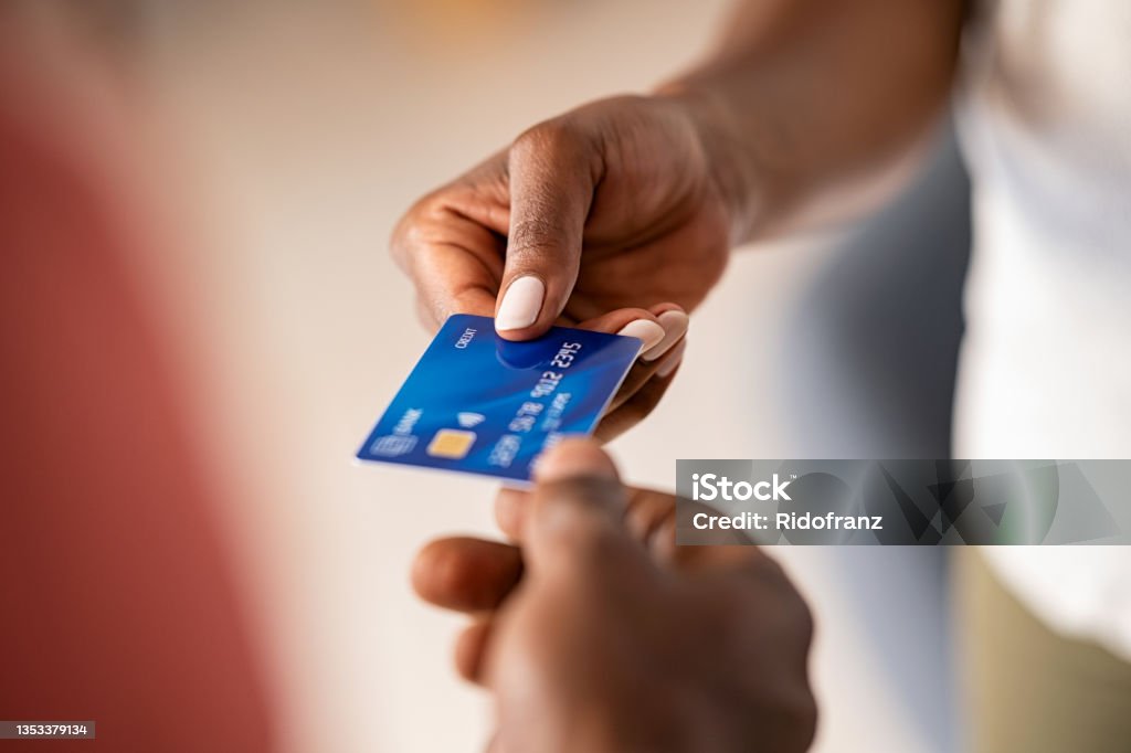 Black woman paying with credit card Close up hands of a black woman giving bank credit card to man. Detail shot of a woman passing a payment credit card to the seller. Hand of african american man receiving payment from customer. Credit Card Stock Photo