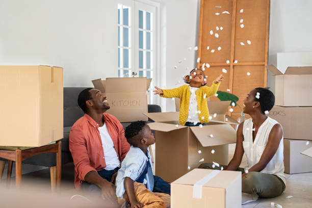 feliz familia afroamericana jugando en una casa nueva con material de relleno de cajas - lanzar actividad física fotografías e imágenes de stock