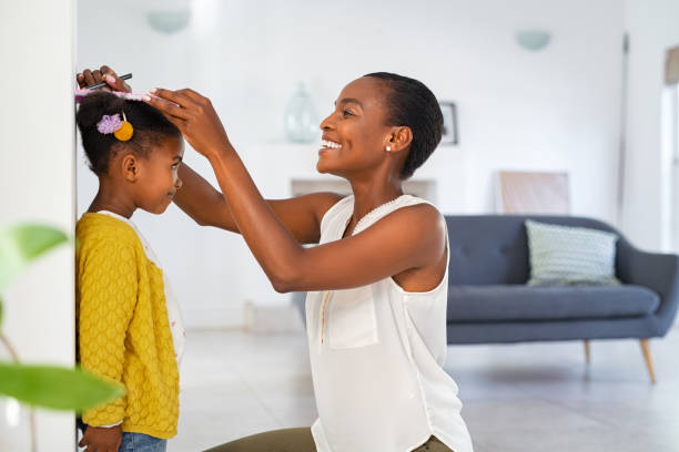 lovely black mother measuring daughter height against wall at home - tall human height women measuring imagens e fotografias de stock