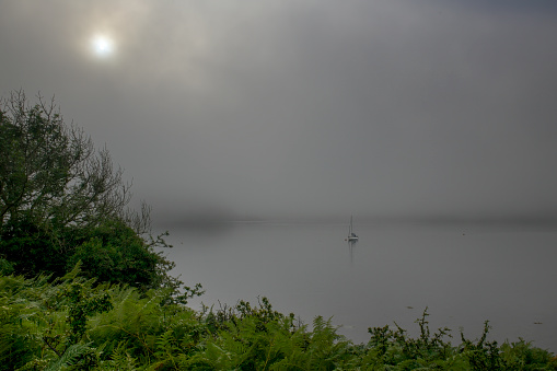 View of moored yacht on a misty morning from the shores of the Isle of Kerrera close to Oban Harbour, Argyllshire in Scotland.