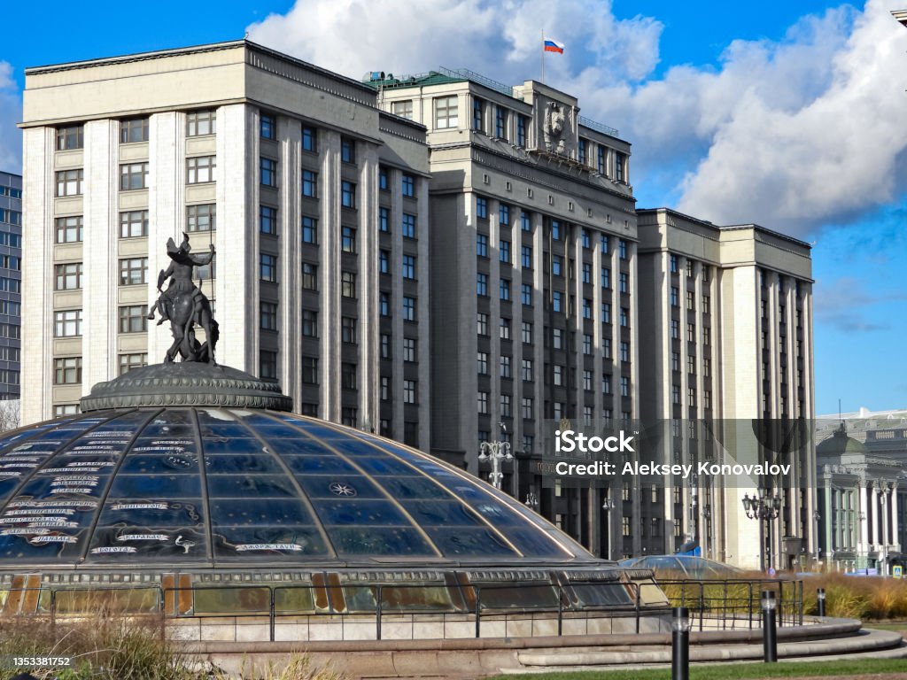 State Duma building in Moscow Moscow, Russia - October 25, 2021: Building of the State Duma of the Russian Federation in Moscow. The main facade of the building. Coat of arms of the USSR. Russian flag. Sculpture of George the Victorious on the dome of the Peace Clock fountain on Manezhnaya Square. Architecture Stock Photo