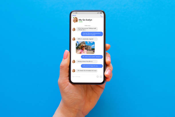 istock Woman using messaging app on her phone, mockup of sample chat application interface on blue background 1353383923