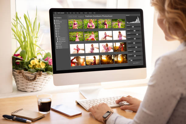 Woman editing digital photos on desktop computer stock photo
