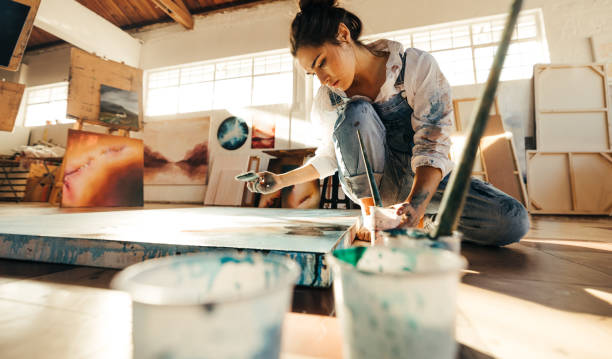 istock Artist painting on a canvas on the floor 1353384241