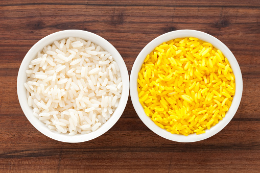 Top view of two bowls side by side with boiled white and saffron rice