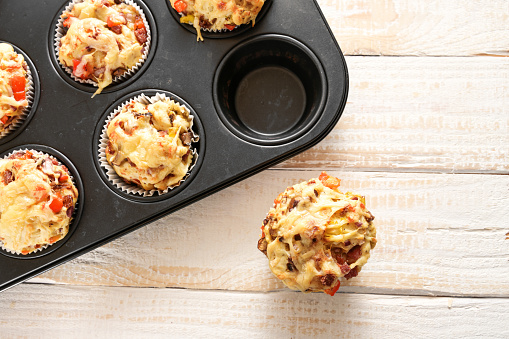 Homemade finger food as party snack, pizza muffins baked in a tray on a wooden table, high angle view from above, copy space, selected focus, narrow depth of field