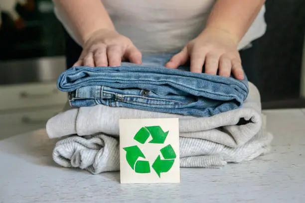 Photo of Garment recycling concept. A stack of clothes is on the recycling table. Collection of clothes for recycling
