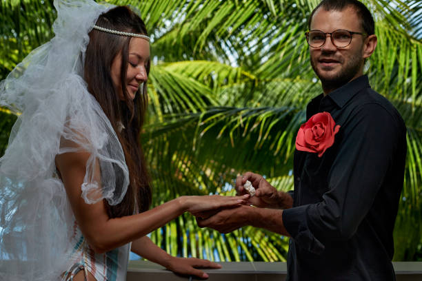 istock Couple Exchanging seashell Wedding Ring against tropical background 1353390034