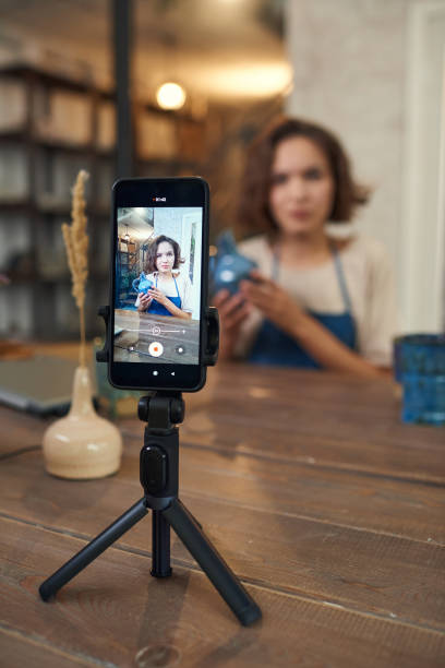istock Smartphone on tripod with young craftswoman on screen 1353393580