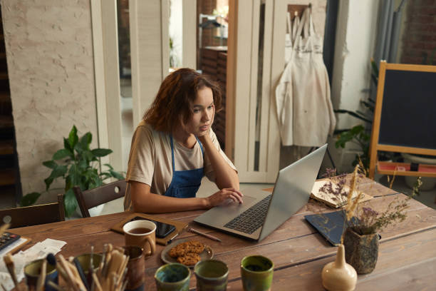 istock Young creative woman concentrating on network while sitting in workshop 1353393597