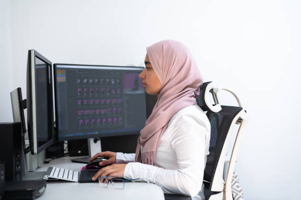 istock Female Arabic creative professional working at home office on desktop computer with dual screen monitor top view. Selectve focus 1353395262