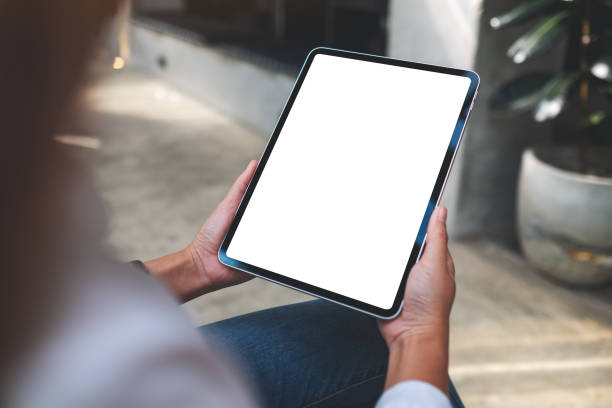 a woman holding digital tablet with blank white desktop screen in cafe Mockup image of a woman holding digital tablet with blank white desktop screen in cafe cafe tablet stock pictures, royalty-free photos & images