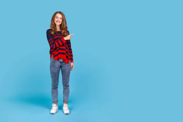 istock Woman points finger aside, showing copy space for commercial text, blank wall with idea presentation 1353399069