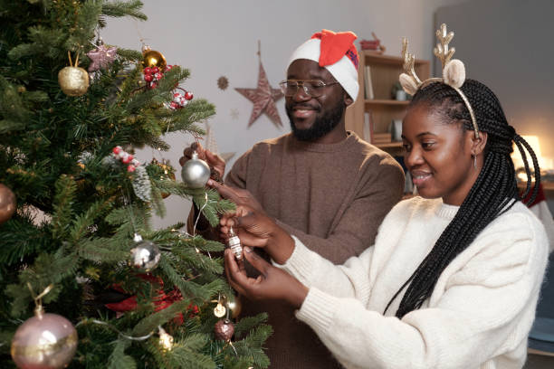 istock Young African couple decorating evergreen tree with toys 1353399188
