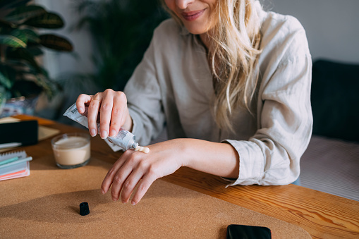 Una mujer anónima que se aplica crema hidratante en las manos photo
