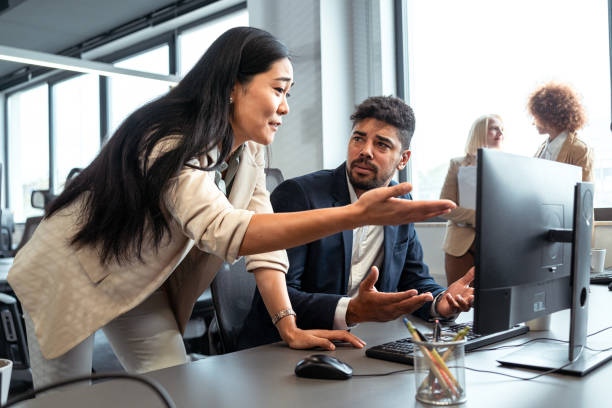 disappointed asian businesswoman, arguing with her mixed-race male coworker in the office - frustration computer confusion businessman imagens e fotografias de stock