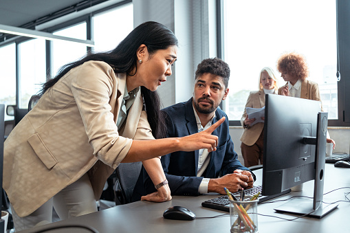 In the office, displeased female CEO of Asian ethnicity, scolding her male mixed-race employee, over the job he didn't do it in the right way