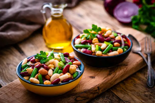 Healthy eating and vegan food: close up view of two bowls of fresh healthy bean salad shot on rustic wooden table. High resolution 42Mp studio digital capture taken with Sony A7rII and Sony FE 90mm f2.8 macro G OSS lens