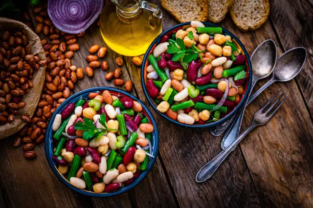 Healthy eating and vegan food: overhead view of two bowls of fresh healthy bean salad shot on rustic wooden table. High resolution 42Mp studio digital capture taken with Sony A7rII and Sony FE 90mm f2.8 macro G OSS lens