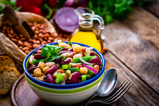 Healthy eating and vegan food: close up view of a bowl of fresh healthy bean salad shot on rustic wooden table. The composition is at the left of an horizontal frame leaving useful copy space for text and/or logo at the right. High resolution 42Mp studio digital capture taken with Sony A7rII and Sony FE 90mm f2.8 macro G OSS lens