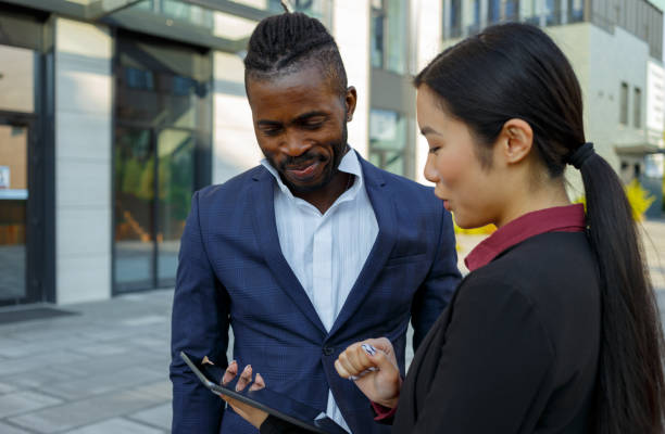 istock African American man and Asian woman check work with tablet 1353407191