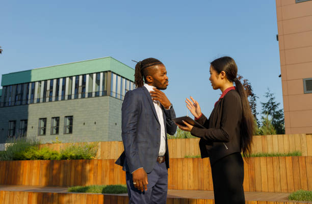 African American man and Asian woman communicate near office stock photo