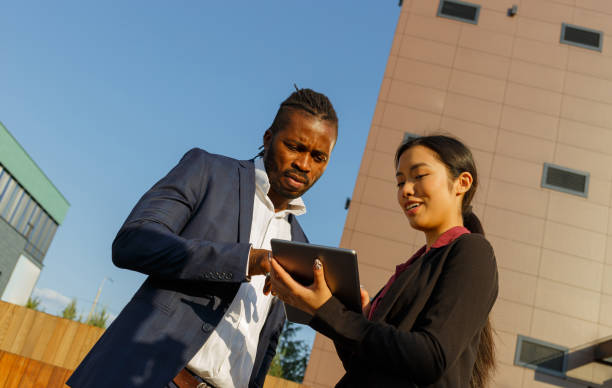 istock Black man and Asian woman discuss work via tablet at sunset 1353407258