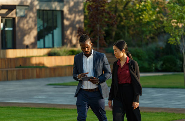 istock Black man and Asian woman stroll with tablet in hands 1353407514
