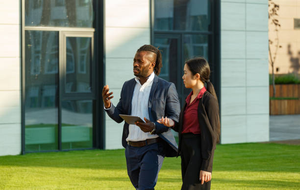 istock Black man and Asian woman stroll with tablet in hands 1353408356