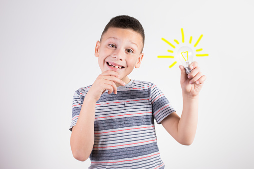 Thinking child boy on white background with light bulb, studio shot