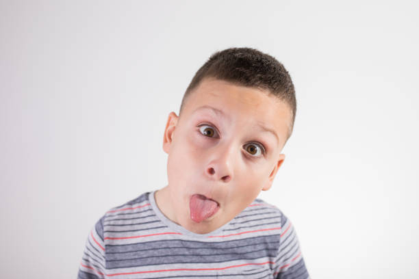 portrait of funny naughty little boy in t-shirt sticking out tongue - careless child rudeness little boys imagens e fotografias de stock