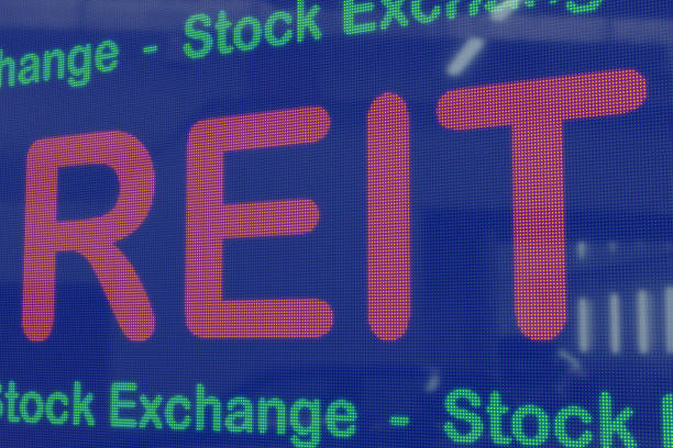 istock REITs (Real Estate Investment Trusts) on a blue LED screen framed by the text stock exchange in green. 1353410779