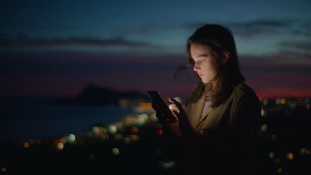 Young woman look at phone in sunset light