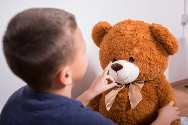 istock Little boy plays with teddy bear 1353413945