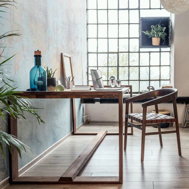 istock Stylish loft interior design. Open space. Home decor. Wooden table, desk with design accessories. Template. 1353416255
