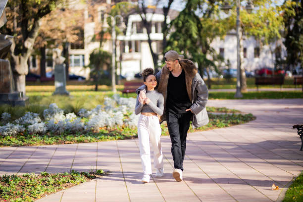 istock Young couple walking in public park 1353416378