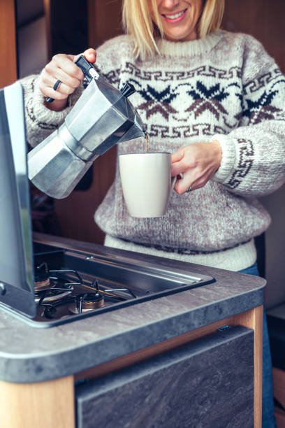 istock Woman serving coffee with coffee maker in camper van 1353417870