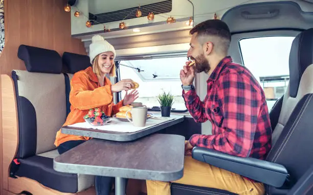 Photo of Friends having breakfast in a camper van in the morning