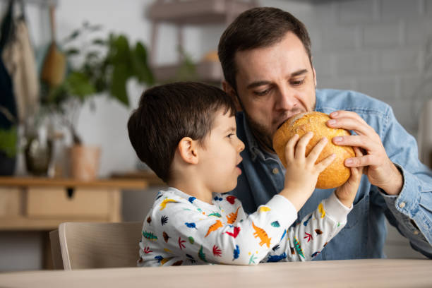 istock Adorable little boy sharing bread with his dad. 1353418885