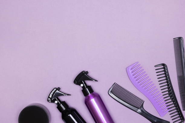 istock Hair styling product bottles with combs on purple background. Flat lay. Copy space 1353420389